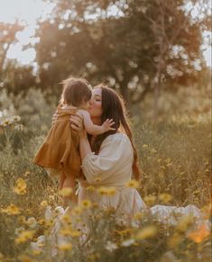 a mother and her child are kissing in the middle of a field full of wildflowers