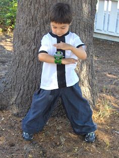 a young boy standing next to a tree