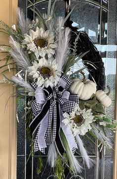 a wreath on the front door decorated with white flowers and black ribbon is hanging from an iron gate