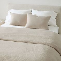 a bed with white sheets and pillows in a bedroom