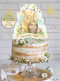 there is a cake with a bear on it and the words welcome baby written in gold