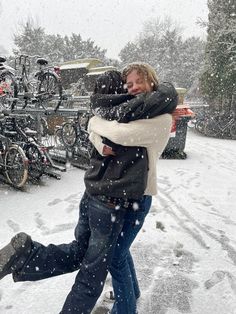 a man and woman hugging in the snow with bicycles behind them on a snowy day