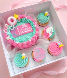 a pink and blue cupcake in a box with other cupcakes around it