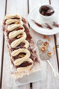 there is a piece of cake with nuts on it next to a cup of coffee