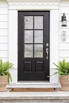 a black front door with two planters next to it