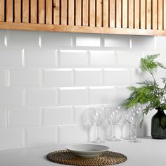 there is a plate and wine glasses on the counter in this kitchen with white tiles