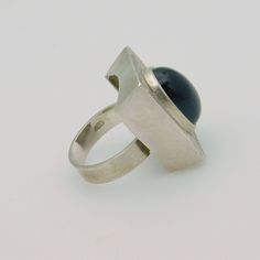 Wonderful mid-century modern sterling ring set with a large black stone (probabaly glass).  The face or setting of the ring is a rectangle shape with 5/16 inch deep sides.  Finely lined rays go all the way around the stone.  Adjustable band is a nice flat band, and fairly wide, making it very comfortable. The face measures about 1 inch front to back and 3/4 inch side to side.  Mark is double stamped making it unreadable but it tests as sterling. Condition is very good - it looks to me like this Modern Silver Ring With Rectangular Stone, Modern Silver Rings With Rectangular Stone, Rectangular Sterling Silver Rings In Modernist Style, Modern Black Ring With Rectangular Stone, Best Flats, Mid Century Mod, Sterling Jewelry, Modern Ring, Ring Black