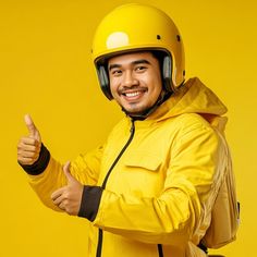 a man in a yellow jacket and helmet giving the thumbs up sign with his hand