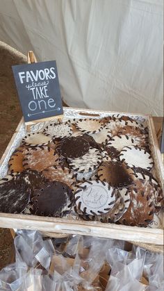 an assortment of brown and white cookies on display in a box with a sign that says favors to make one