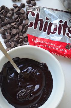 a bowl of chocolate pudding next to a bag of choclate chips on a table