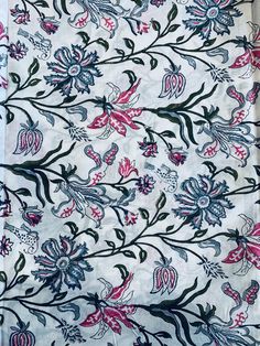 an embroidered fabric with flowers and leaves on white, blue, red and black colors