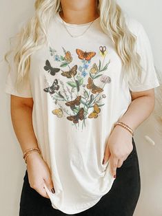 Looking for the perfect gift for the biologist or nature lover in your life? Look no further than our vintage floral and butterfly shirt! Featuring a gorgeous monarch butterfly and intricate floral designs, this shirt is the ultimate piece of botanical clothing. The cute butterfly tee is crafted from high-quality, lightweight fabric, ensuring both style and comfort. Whether you're dressing up or down, this butterfly species apparel is perfect for any occasion. So why wait? Show off your love for Vintage White Tops With Plant Print, Cottagecore Printed Crew Neck T-shirt, Nature-inspired Relaxed Fit Short Sleeve Tops, Nature-inspired Cotton Tops With Graphic Print, Vintage T-shirt With Plant Print, Short Sleeve, Cottagecore Graphic Print T-shirt, Cottagecore Graphic Print Short Sleeve T-shirt, Nature-inspired Crew Neck Top With Plant Print, Nature-inspired Top With Plant Print And Crew Neck