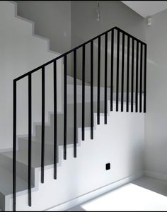 an empty room with white walls and black railings on the bottom floor, next to a set of stairs