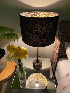 a lamp that is sitting on top of a table next to a vase with flowers