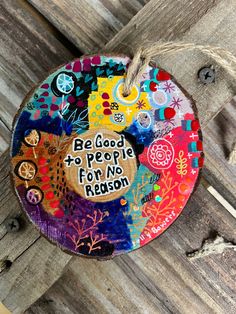 a colorful ornament hanging on the side of a wooden fence that says, be good to people for no reason