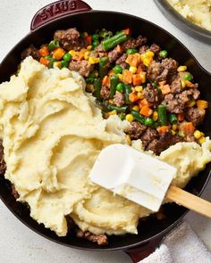 mashed potatoes and ground beef in a skillet with a spatula on the side