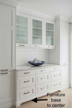 a kitchen with white cabinets and glass doors