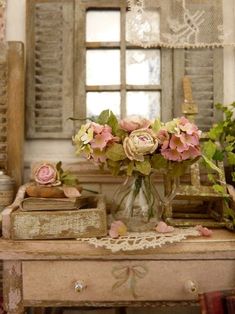 a vase filled with pink flowers sitting on top of a table next to two books