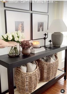 a table with baskets and flowers on it in front of four framed pictures, one is white tulips