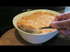 a person holding a spoon in a casserole dish