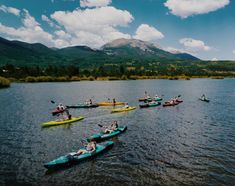 a group of people riding kayaks on top of a lake