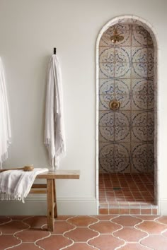 two white towels hanging on the wall next to a wooden table and bench in a bathroom