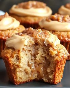 some cupcakes with frosting on top are sitting on a black plate and one is cut in half