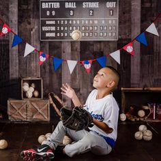 a young boy sitting on the floor in front of a baseball bat and ball display