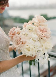 a woman holding a bouquet of white and pink flowers in her hand on a balcony