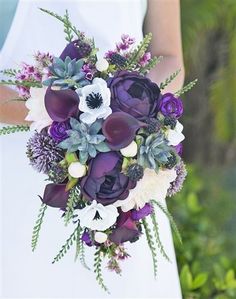 a bride holding a purple and white bouquet with succulents on her wedding day