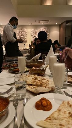 people are sitting at a table with food and drinks in front of them as they prepare to eat