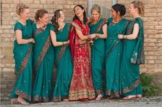 a group of women standing next to each other wearing green and red sari dresses