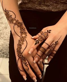 two hands with henna tattoos on them, one is holding the other's hand