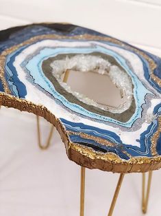 a table that has some kind of blue and gold design on it, with metal legs