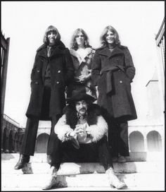 four women in coats and furs posing for a photo on the steps outside an old building