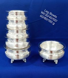 a stack of silver bowls sitting next to each other on top of a blue background