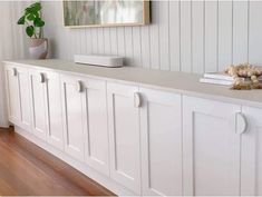 a room with white cabinets and wood flooring next to a painting on the wall