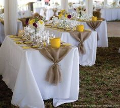 the table is set with yellow and white flowers, candles, and wineglasses