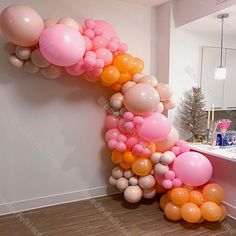 the balloon arch is decorated with pink, orange and white balloons