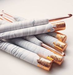 four pens with gold and white paint on them are lined up in a pyramid shape