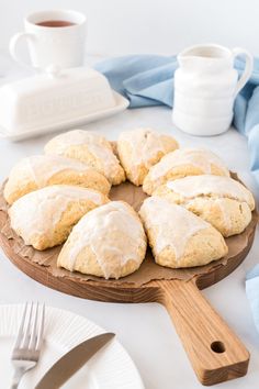 a wooden platter filled with frosted scones on top of a table