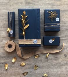 blue wrapping paper with gold foil leaves and ribbon on wooden table next to two rolls of twine