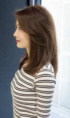 a woman standing in front of a window with her hands on her hips and looking out the window