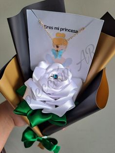 a person holding a card with a white rose on it and a green ribbon attached to it