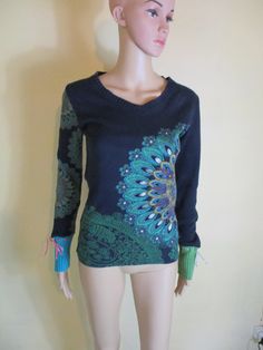 Vintage Desigual  sweater.  The background is very dark navy cotton with a vibrant flower print on the the back and front in  mostly greens and blues.  The front has sequins and glitter in the  print.  It has a V neck and long knitted sleeves.  One sleeve has the flower print and the cuffs are one green and one blue with a velvet ribbon.  This item is in good vintage condition. Size;  UK 12  US 10  EU 40     Please check your measurements with the listing as sizes vary  brand to brand. Bust flat Fitted Bohemian V-neck Sweater, Vintage Floral Print Winter Tops, Vintage Winter Floral Print Tops, Bohemian V-neck Tops For Winter, Hippie Patterned Tops For Fall, Bohemian Cotton V-neck Sweater, Bohemian Floral Print Winter Sweater, Bohemian Floral Print Sweater For Fall, Bohemian Knit Tops For Winter