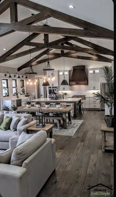 a living room filled with furniture next to a kitchen and dining room table on top of a hard wood floor