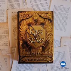 the king of scars book is laying on top of some old books with paper scattered around it