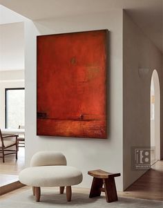 a painting hanging on the wall above a chair and footstool in a living room