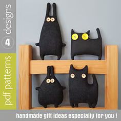 three black cats sitting on top of a wooden shelf next to each other with yellow eyes