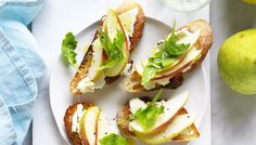 an apple and cheese sandwich on a white plate next to some pears, lemons and water